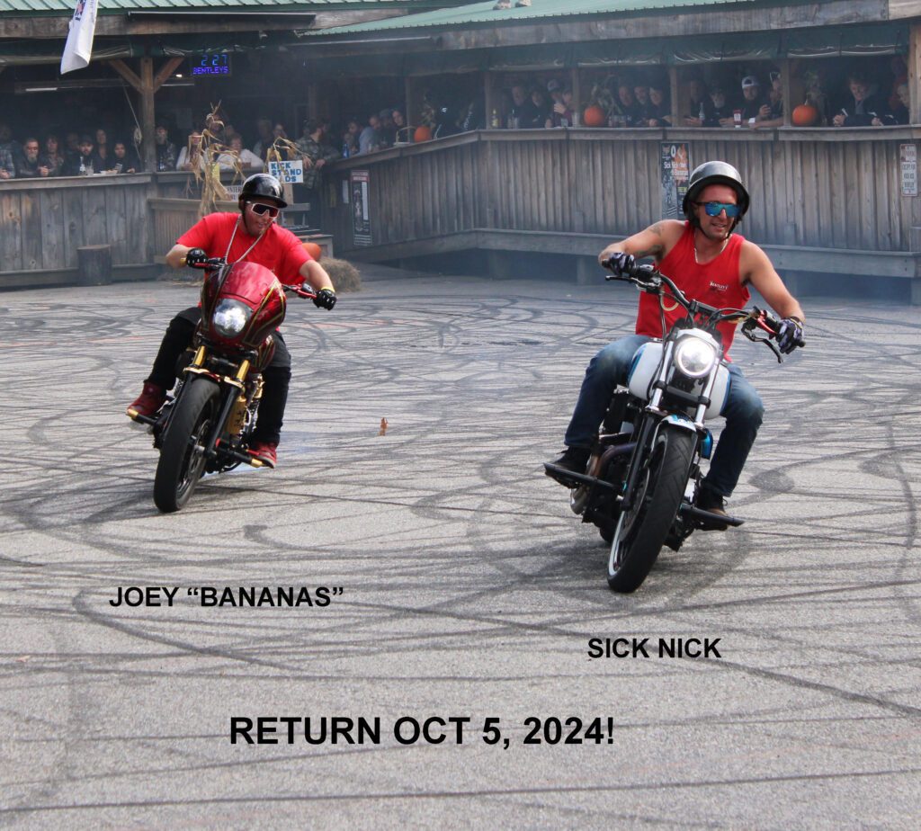 Two people on motorcycles in a parking lot.