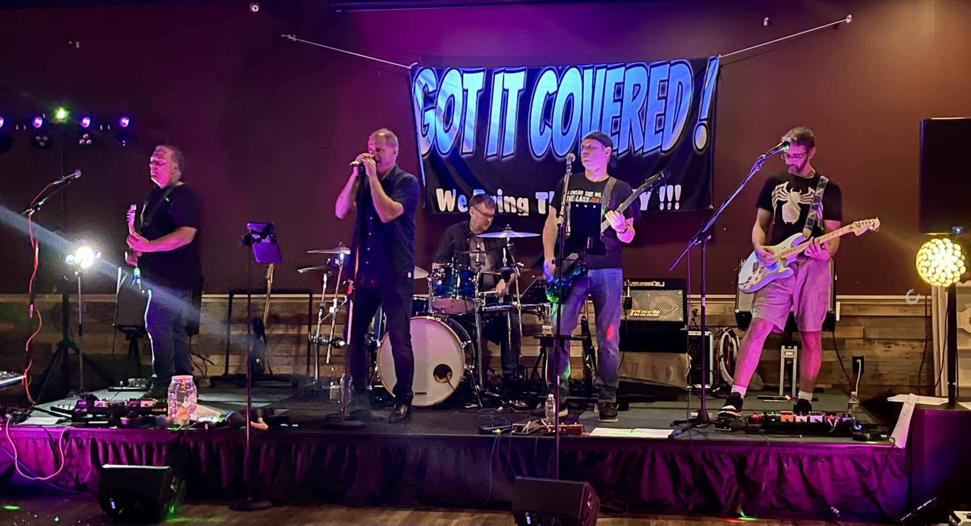 A band performing on stage with the words " got it covered ".