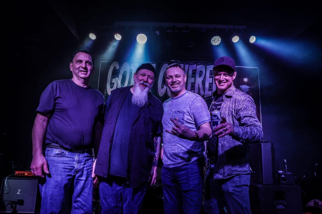 Four men posing together on stage with a glowing backdrop.