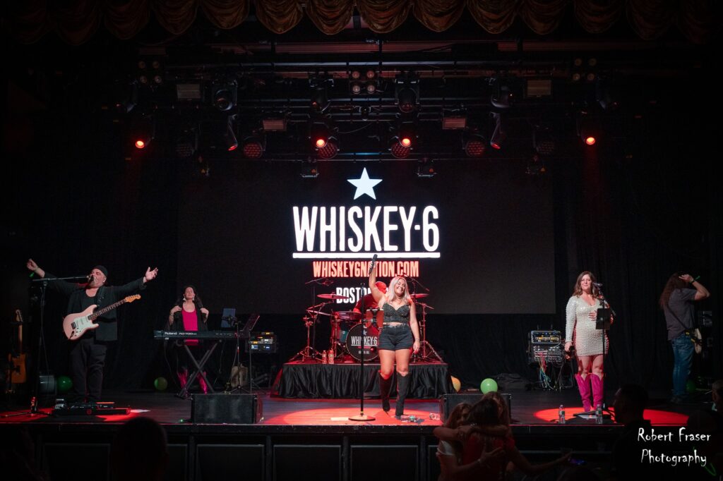 Band Whiskey-6 performing live on stage with instruments and vocalists.
