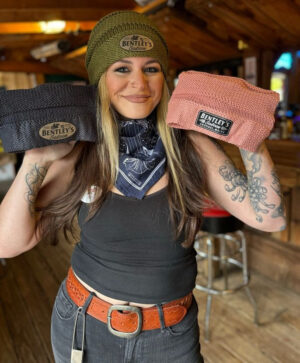 Woman smiling while holding two pouches in a rustic setting.